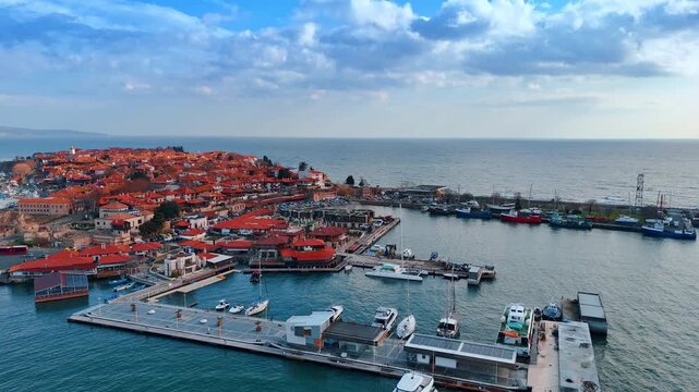 Close up aerial view of marina and old town harbor. Detailed shot of docked boats, yachts and waterfront buildings in a historical coastal port.