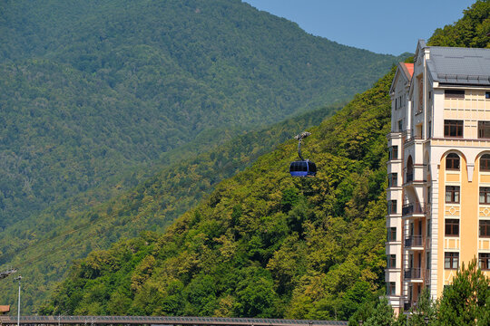 Cabin ascends along cable car located next to hotel in forested area.