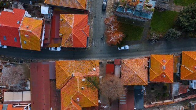 Top down aerial shot of old town streets. Directly overhead view of orange tiled roofs, cobblestone streets, and parked cars in a historic town.