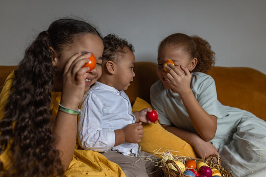 Children painting Easter eggs together at home during spring celebration