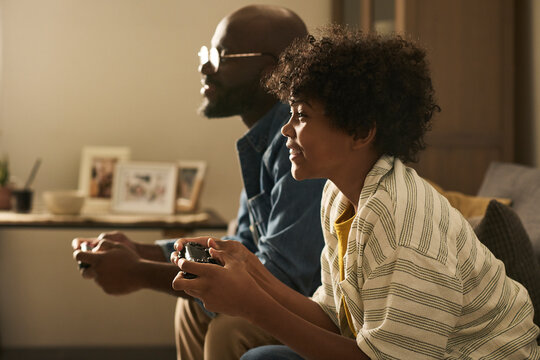 Father and son playing video game together at home in living room