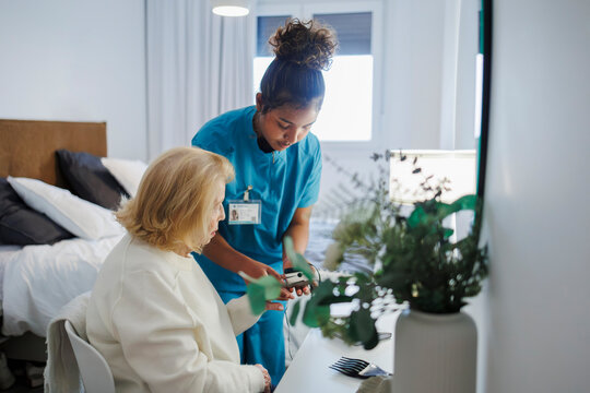 Nurse supporting senior with reading in comfortable indoor setting