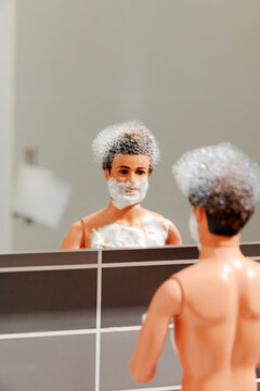 Plastic figure with foam on beard and chest grooming at bathroom mirror