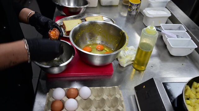Professional chef cracking many eggs in a restaurant kitchen
