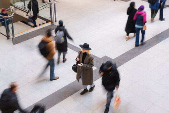 Urban commuter waiting at public station with smartphone in motion crowd
