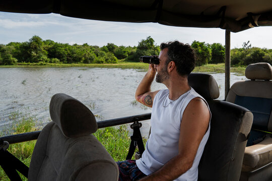 Man on safari jeep with binocular observing nature Sigiriya outdoors