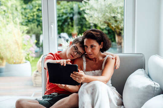 Mother and son with trisomy 21 bonding while using tablet at home