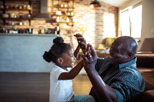 Grandfather and granddaughter playing together at home in kitchen