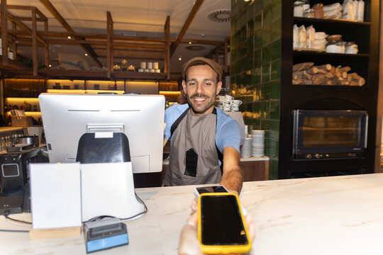 Bartender receiving contactless payment with smartphone in cafe