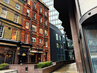 Historic red brick and modern glass architecture along a narrow city street in London, UK