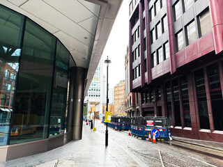 Urban street in London, UK with modern office buildings and wet sidewalks in business district
