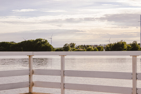 Wooden lake jetty with white railings and wind turbines sunset in Żnin, Kuyavian-Pomeranian Voivodeship, Poland