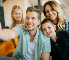 Smiling family of four taking selfie at home