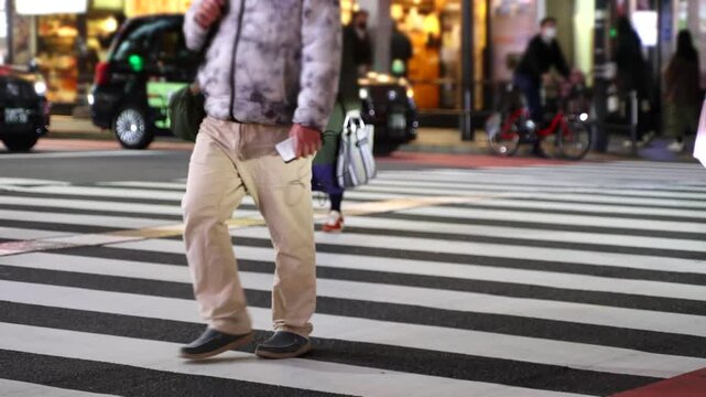People walking in front of wooden vertical slats wall with warm lighting, urban lifestyle scene captured in real time. Ideal for business, lifestyle and modern city background footage.