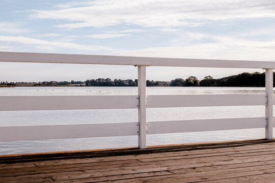 Wooden lake jetty with white railings and wind turbines sunset in Żnin, Kuyavian-Pomeranian Voivodeship, Poland