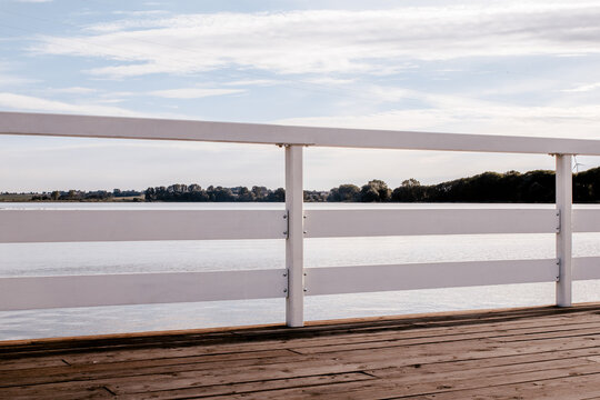 Wooden lake jetty with white railings and wind turbines sunset in Żnin, Kuyavian-Pomeranian Voivodeship, Poland