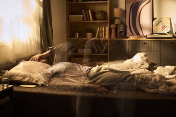 Young woman lying in bed tossing and turning with blurred motion effect suggesting restlessness in bedroom with bookshelf and abstract artwork in background © Mediaphotos