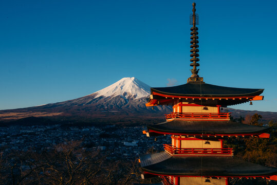View of the red Chureito Pagoda contrasts against the snow-capped peak of Mount Fuji under a clear blue sky, Fujiyoshida, Chuerito Pagoda, Japan.