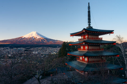 View of the vibrant red Chureito Pagoda standing tall against the backdrop of snow-capped Mount Fuji, embodying peace and tradition, Fujiyoshida, Japan.