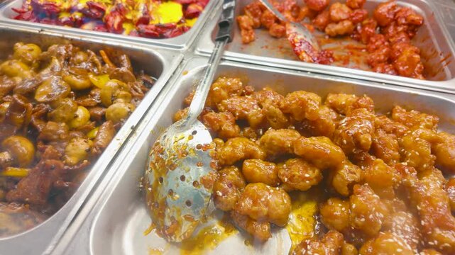 Assorted Asian buffet hot trays with mushroom stir-fry and orange chicken