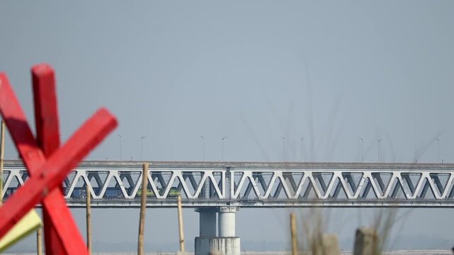 Steel bridge with geometric pattern and distant train in motion