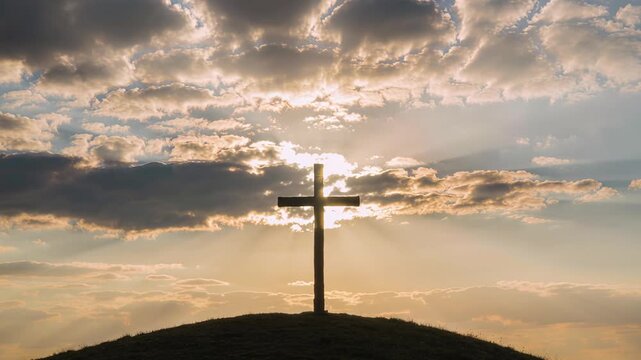 Radiant cross on hill under vivid sunset with clouds overhead