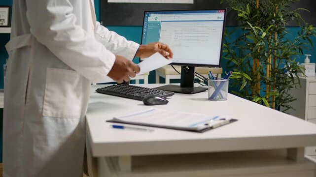 Placing sheet onto clipboard, Dr in coat reviewing records, handling papers at desk, copy space