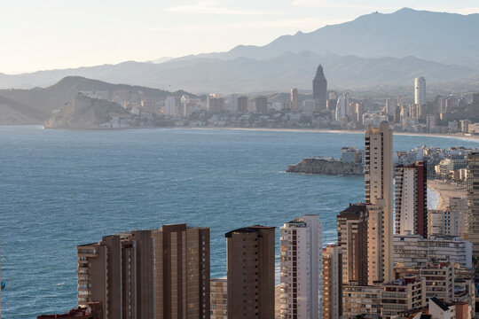 Highrise urban skyline over sea coast bay with mountains in Benidorm Spain seen in daylight showing layered city and shoreline scenery