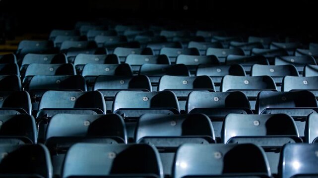 Showing fold-up seats reflecting cool spots after camera shift for empty arena, with number plates