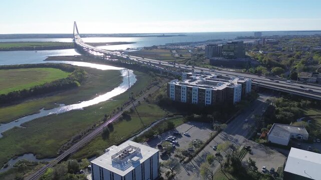 Marsh channels curve beneath the Arthur Ravenel Jr. Bridge near Morrison Dr and North Morrison district. Sunlit rooftops and reflective water textures frame mixed urban edges in South Carolina