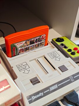 Russia, St. Petersburg, March 14, 2026 -Vintage Dendy video game console with a colorful game cartridge on display