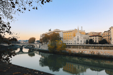 Fototapeta premium Classical architecture and arched bridge over river with soft evening tones and reflections creating timeless urban landscape in Italy.