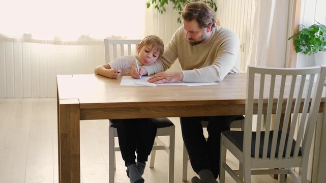 Dad teaches his son writing and counting. Kids primary education. Children learn, study in home school. Daddy male helping teaching little child boy support studying, learning homework. Knowledge day.