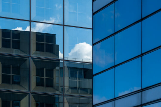 Blue grid facade architecture with modern glass windows reflection of sky clouds creating clean geometric pattern texture for abstract background