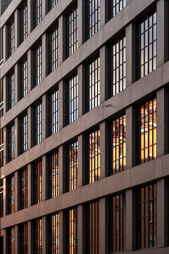 High contrast sunlight on modern office building architecture facade with glass windows and grid structure forming bold abstract pattern background