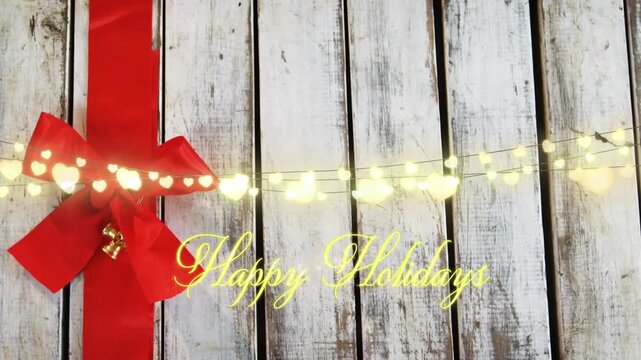 Animation of text, happy holidays, in yellow with string lights and red christmas bow decoration