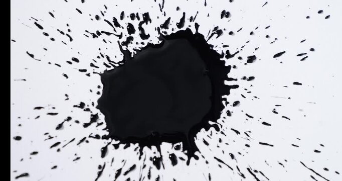 Black spots on a white background. Ink spills onto white paper. Black drops and white surface.