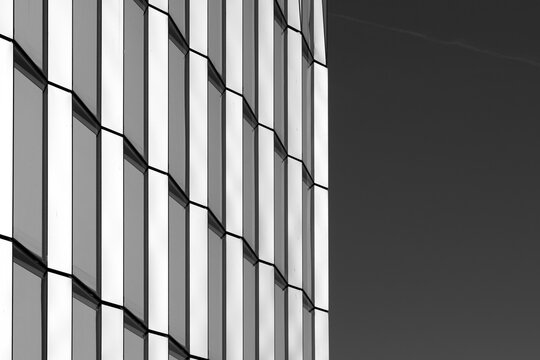 Monochrome building architecture facade with modern grid lines forming abstract geometry pattern and strong urban texture for minimal design background