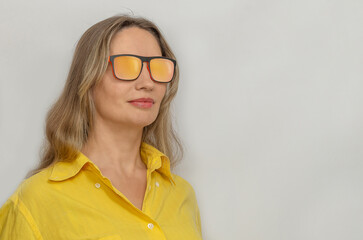 Fototapeta premium Confident woman in yellow shirt wearing stylish sunglasses isolated on light background. Copy space.
