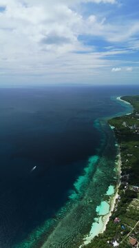 Vertical drone descends from high altitude over reef edge and coast near Bohol Beach in Panglao, Bohol