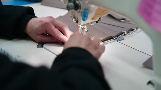 Tailor hands sewing fabric on an industrial machine