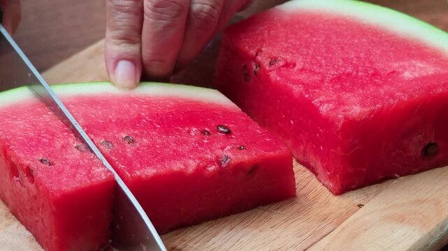 Closeup of hands cutting watermelon on the board.