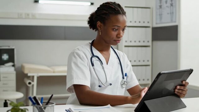 Vertical video: Tapping tablet, nurse in white scrubs with stethoscope reviewing notes at clinic
