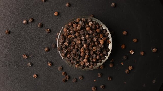 Top View of Black Pepper Seeds (Kali Mirchi) in Bowl on Black Background &ndash; Rotating Footage