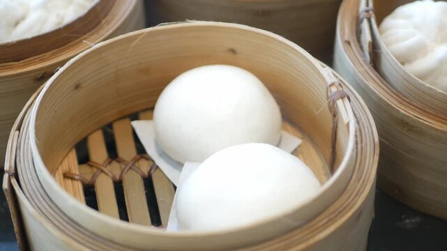 close up view to a steamer full with chinese bun dimsum in hongkong style with hot streaming ready to eat in panning view,chinese dimsum food eating