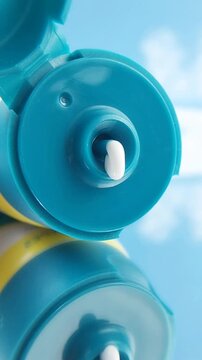 Close up of white cream flowing from turquoise packaging, smooth skincare texture with clean minimal aesthetic.