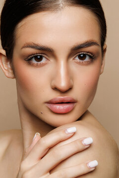 Beautiful young woman with clean fresh skin on beige background, Face care, Facial treatment, Cosmetology, women portrait.