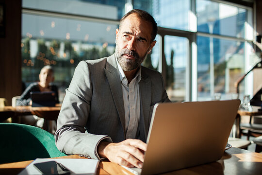 Mature businessman working on laptop in modern cafe