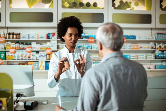 Pharmacist advising senior customer at drugstore counter