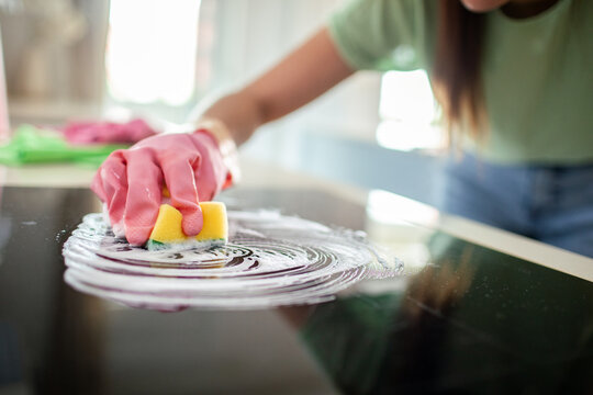 Woman cleaning glass stovetop in kitchen